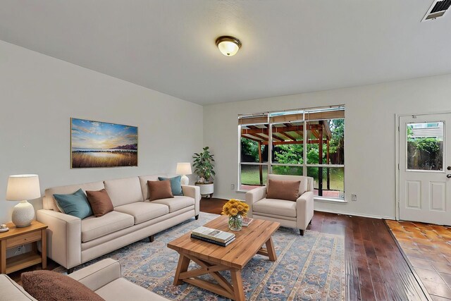 unfurnished living room featuring visible vents, baseboards, a healthy amount of sunlight, and hardwood / wood-style flooring