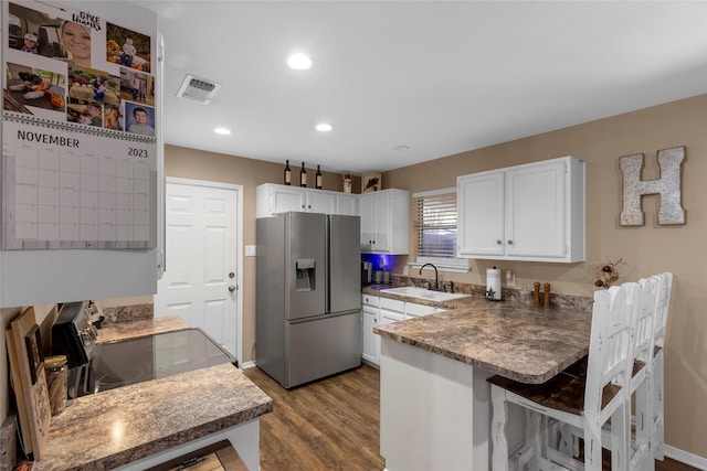 kitchen with a sink, appliances with stainless steel finishes, a peninsula, visible vents, and white cabinets