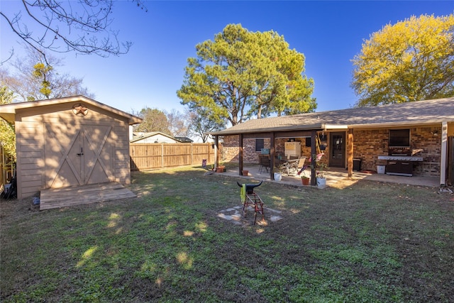 view of yard with a fenced backyard, a shed, an outbuilding, and a patio area