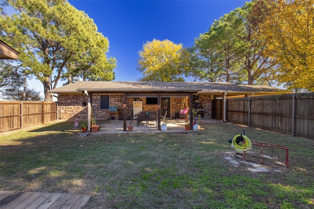 rear view of property featuring brick siding, a fenced backyard, a yard, and a patio area