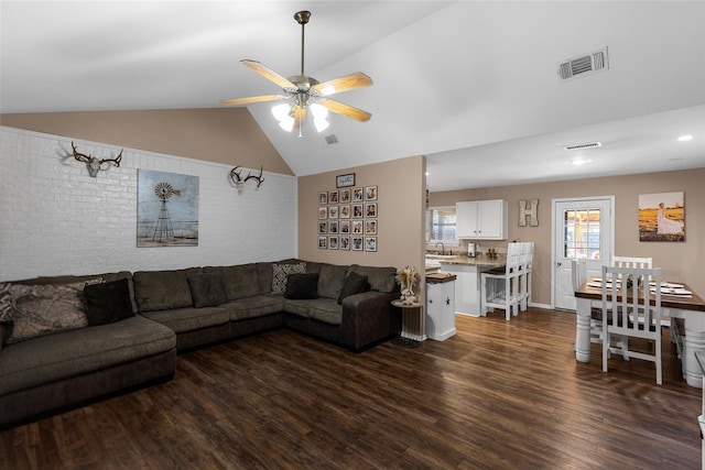 living area with dark wood-type flooring, ceiling fan, visible vents, and vaulted ceiling