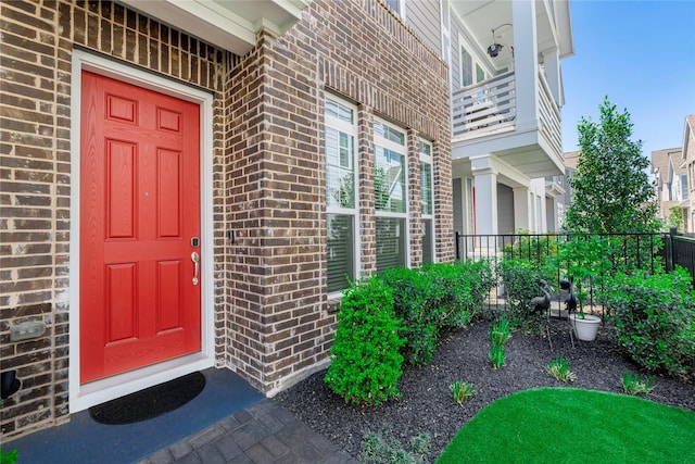 view of exterior entry with brick siding and fence
