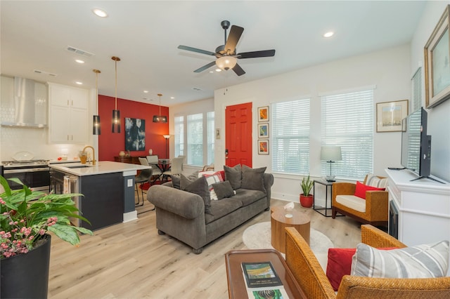 living room featuring visible vents, light wood-style flooring, a ceiling fan, and recessed lighting