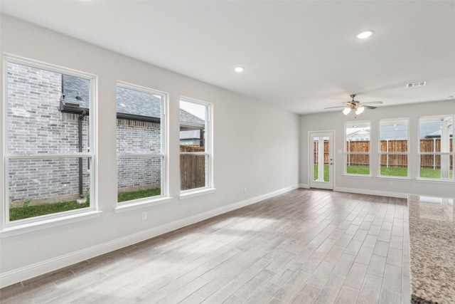 unfurnished living room featuring visible vents, baseboards, and a wealth of natural light