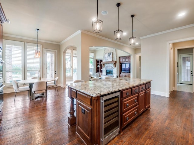 kitchen featuring wine cooler, arched walkways, open floor plan, baseboards, and brown cabinetry