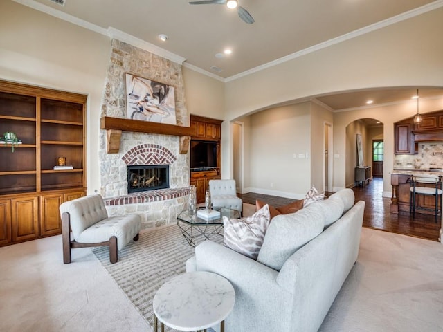 living area with crown molding, ceiling fan, arched walkways, light colored carpet, and baseboards