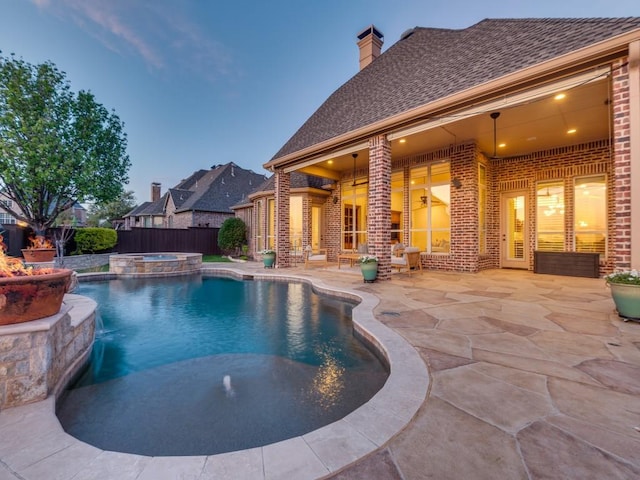 view of pool featuring a pool with connected hot tub, fence, and a patio