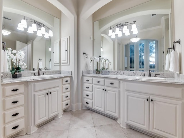 bathroom featuring two vanities, tile patterned floors, crown molding, and a sink