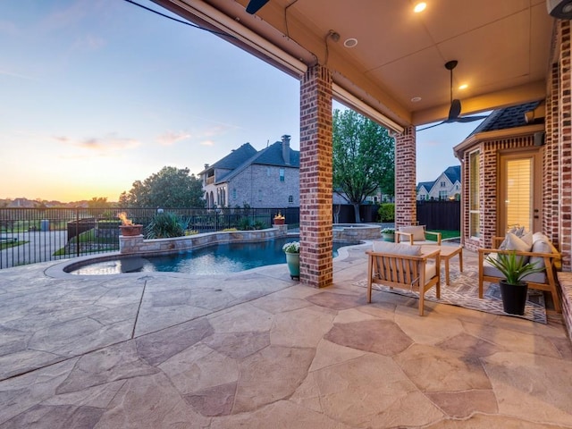 patio terrace at dusk with a fenced backyard, an outdoor living space, and a pool with connected hot tub