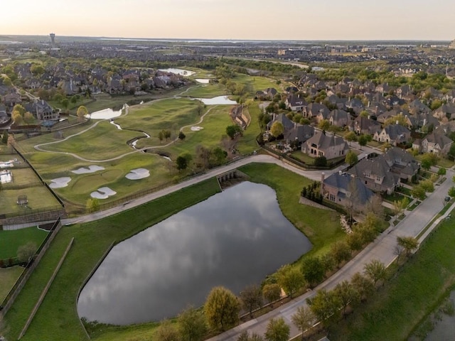 aerial view at dusk with golf course view, a water view, and a residential view