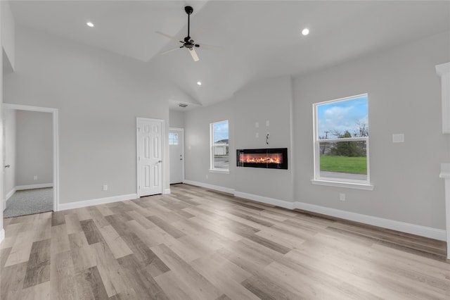 unfurnished living room featuring light wood finished floors, a glass covered fireplace, baseboards, ceiling fan, and recessed lighting