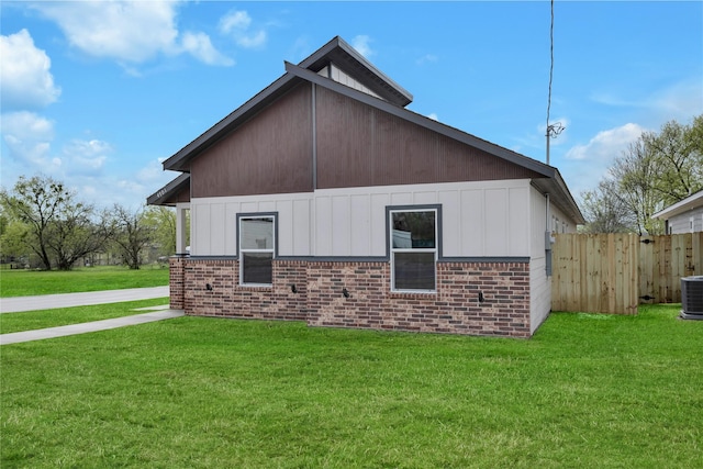 view of home's exterior with cooling unit, brick siding, fence, and a lawn