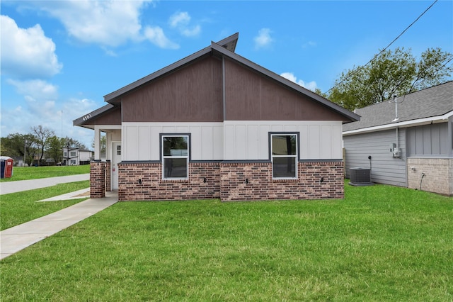 view of side of property with cooling unit, brick siding, and a lawn