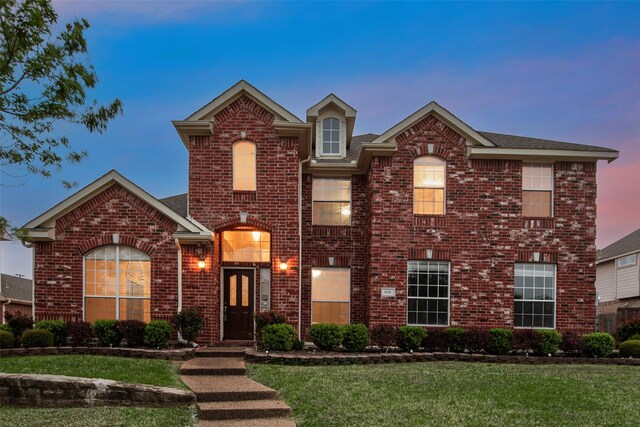 traditional-style house with a yard and brick siding