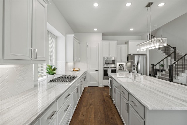 kitchen featuring white cabinets, light stone counters, appliances with stainless steel finishes, and dark wood-style flooring