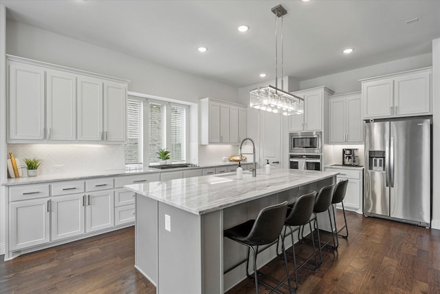 kitchen featuring a sink, white cabinetry, appliances with stainless steel finishes, a center island with sink, and dark wood finished floors