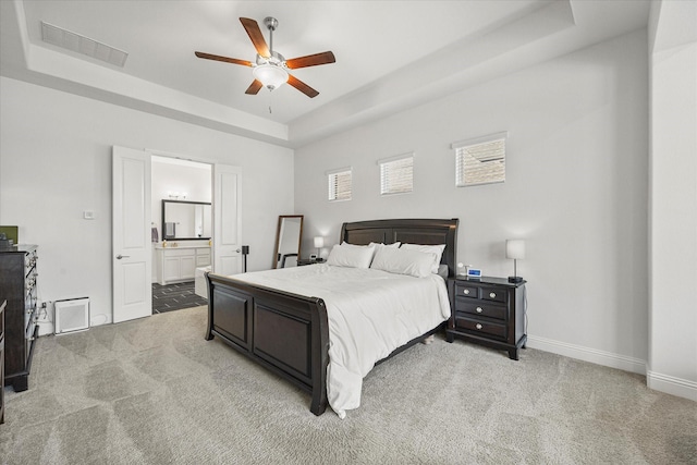 bedroom featuring baseboards, light colored carpet, visible vents, and a raised ceiling