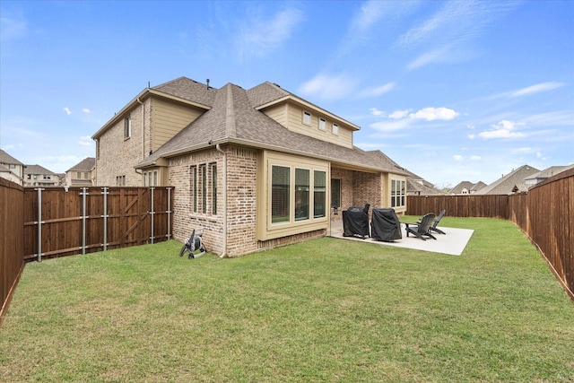 back of house with a lawn, brick siding, roof with shingles, and a patio area