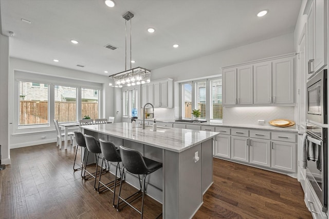 kitchen featuring a sink, tasteful backsplash, appliances with stainless steel finishes, white cabinets, and dark wood-type flooring