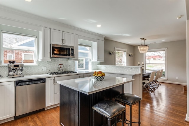 5730 Winton St, Dallas, TX 75206 - kitchen with appliances with stainless steel finishes, a peninsula, light countertops, a breakfast bar, and recessed lighting