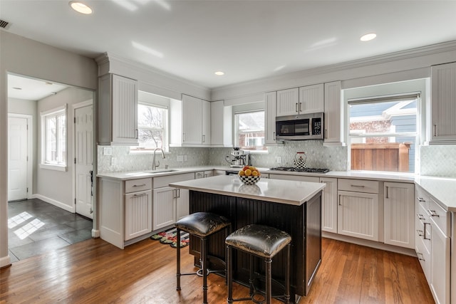 5730 Winton St, Dallas, TX 75206 - kitchen featuring appliances with stainless steel finishes, a breakfast bar, light countertops, a center island, and decorative backsplash