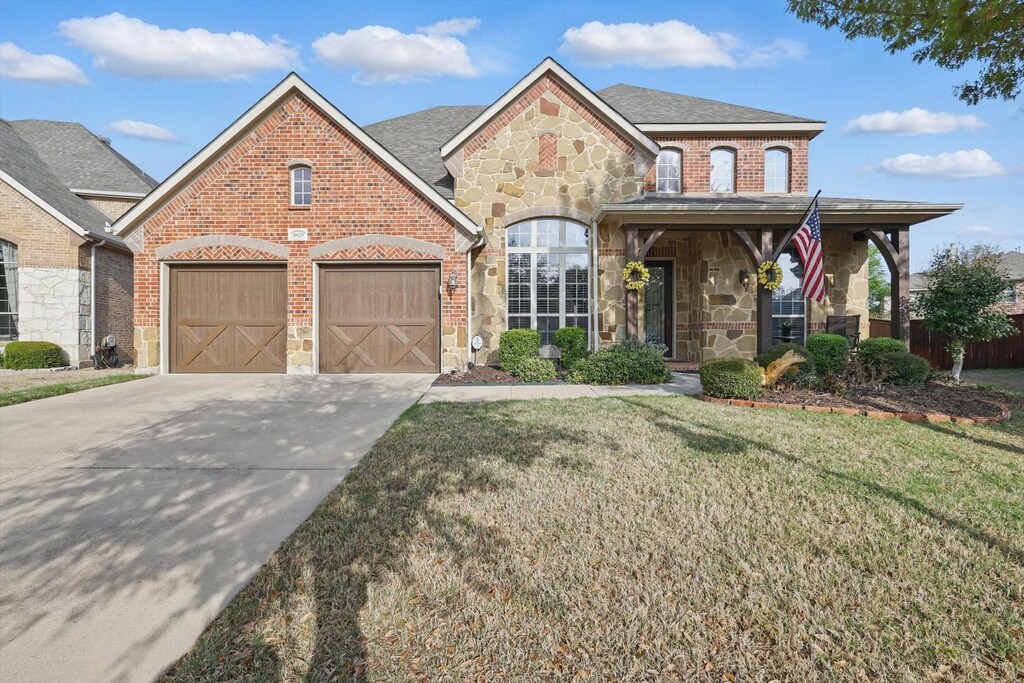 8629 Jefferson Way, Lantana, TX 76226 - view of front of house with stone siding, driveway, a front lawn, brick siding, and a garage