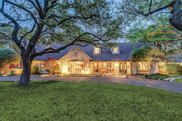 view of front of property with stone siding, covered porch, and a front yard