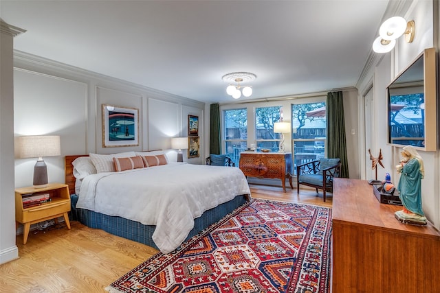 bedroom with light wood-type flooring, a decorative wall, and crown molding