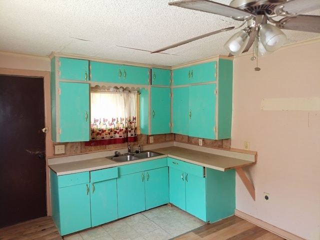 kitchen featuring crown molding, light countertops, a sink, a ceiling fan, and a textured ceiling