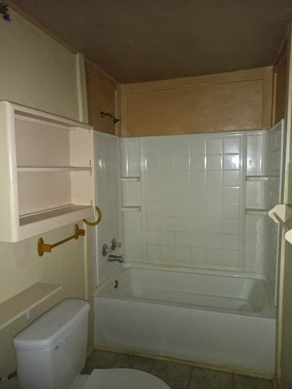 full bath featuring toilet, tile patterned flooring, and washtub / shower combination