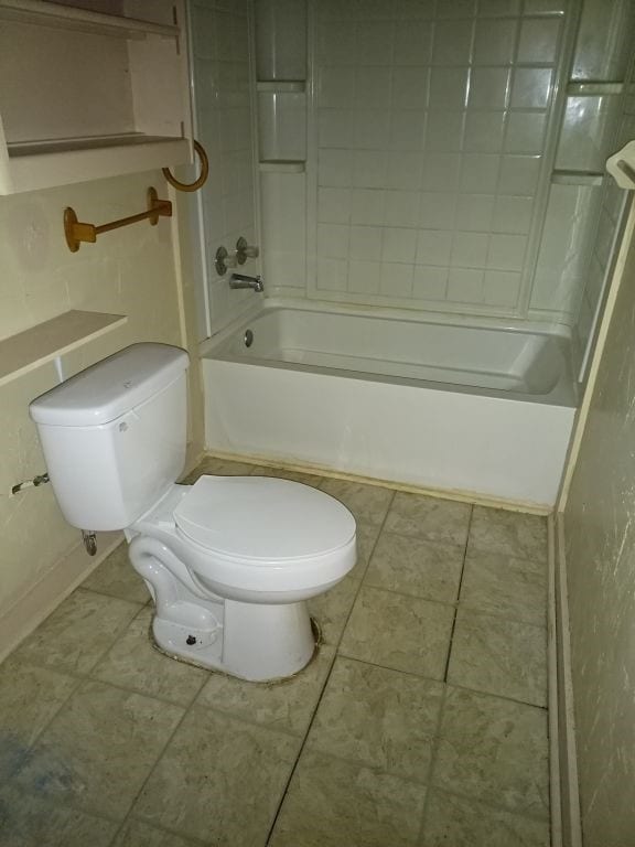 full bath featuring tile patterned floors, toilet, and washtub / shower combination