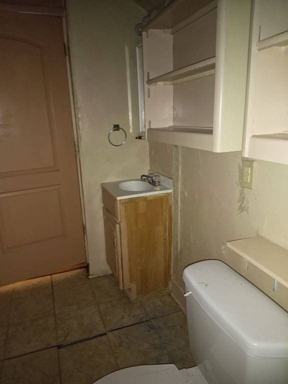 bathroom with toilet, tile patterned flooring, and vanity
