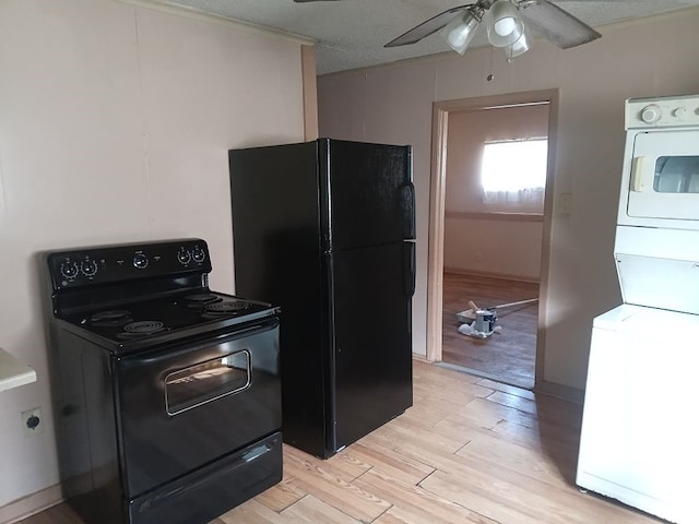kitchen with stacked washing maching and dryer, light wood-style floors, black appliances, and ceiling fan