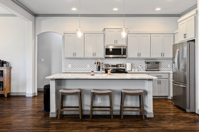 kitchen with light stone countertops, a breakfast bar area, appliances with stainless steel finishes, and dark wood finished floors