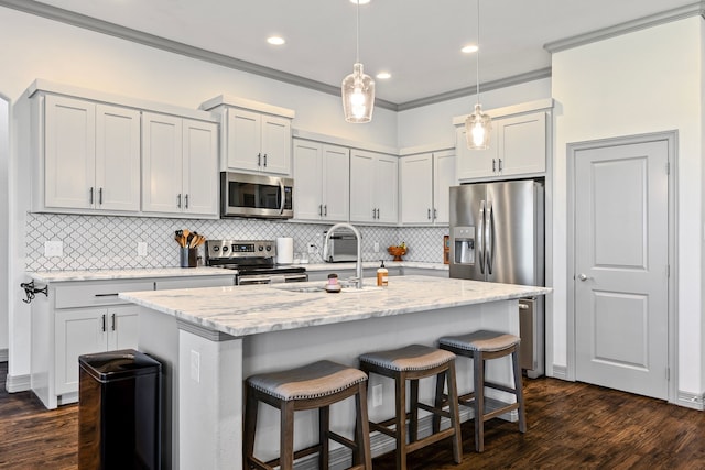 kitchen with ornamental molding, stainless steel appliances, dark wood finished floors, a sink, and a breakfast bar area