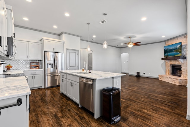 kitchen featuring crown molding, stainless steel appliances, a sink, arched walkways, and visible vents