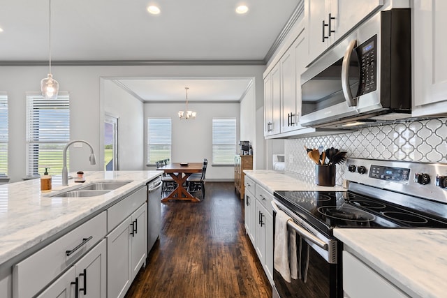 kitchen with decorative backsplash, a sink, crown molding, and appliances with stainless steel finishes
