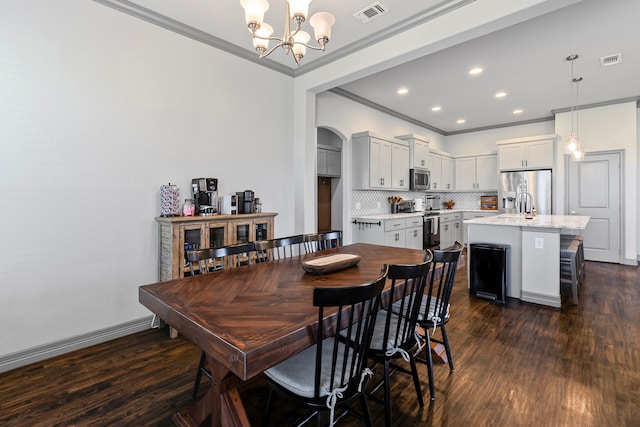 dining area with dark wood finished floors, visible vents, crown molding, and a chandelier