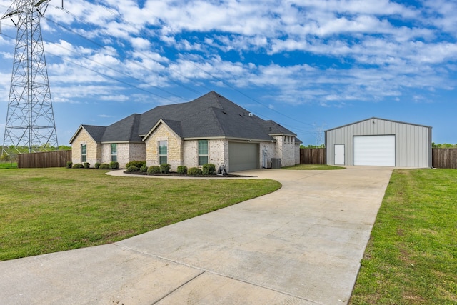 view of front of home with a front yard, a detached garage, fence, and brick siding