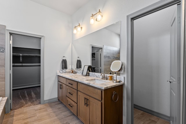 full bathroom featuring a sink, double vanity, and wood finished floors