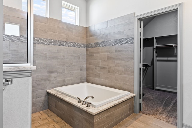 bathroom with a walk in closet and a garden tub