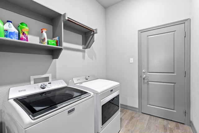 washroom with washing machine and clothes dryer, laundry area, and light wood-type flooring
