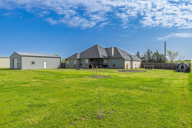 back of house with an outbuilding, fence, a pole building, and a yard