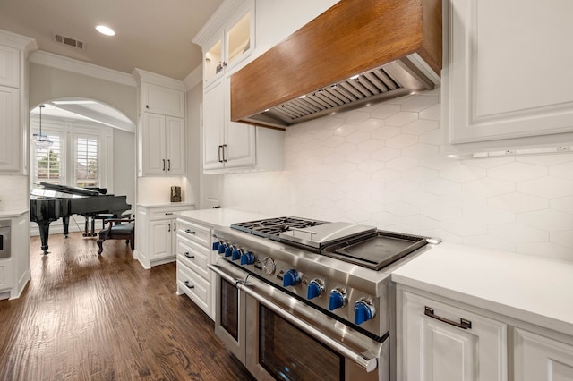 kitchen featuring decorative backsplash, range with two ovens, ornamental molding, custom range hood, and white cabinetry