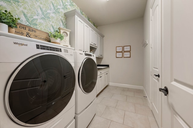 laundry area with baseboards, wallpapered walls, washing machine and clothes dryer, cabinet space, and light tile patterned floors