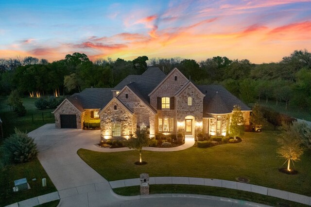 french provincial home with a lawn, curved driveway, and stone siding