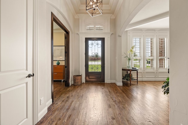 entrance foyer with crown molding, wood finished floors, a notable chandelier, and a wealth of natural light