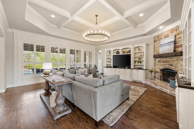 living room featuring crown molding, a notable chandelier, a stone fireplace, and coffered ceiling