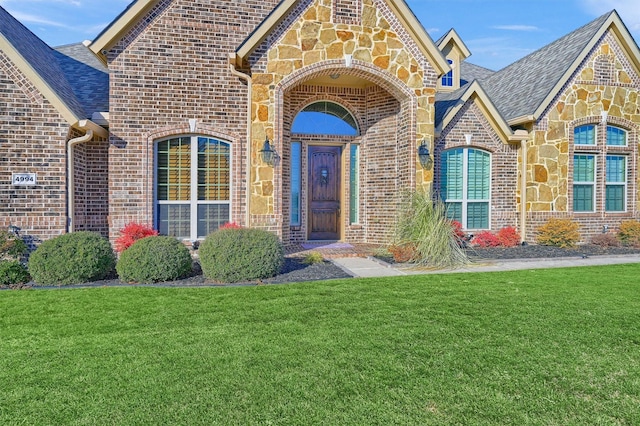 4994 Dogwood Dr, Celina, TX 75009 - property entrance featuring brick siding, a yard, stone siding, and a shingled roof