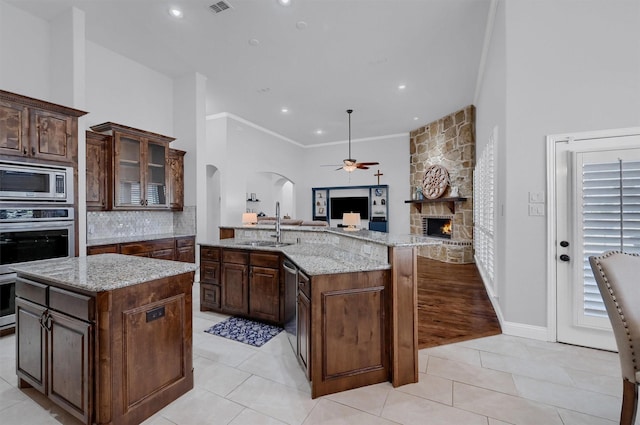 4994 Dogwood Dr, Celina, TX 75009 - kitchen with open floor plan, arched walkways, ceiling fan, appliances with stainless steel finishes, and a stone fireplace